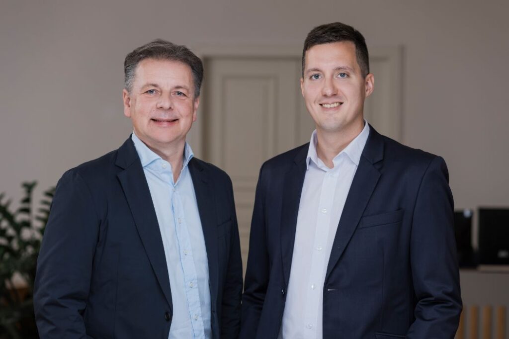 Zwei Geschäftsführer im Anzug vor neutralem Hintergrund – Vorstellung des Teams von P&K Nord ZT-GmbH