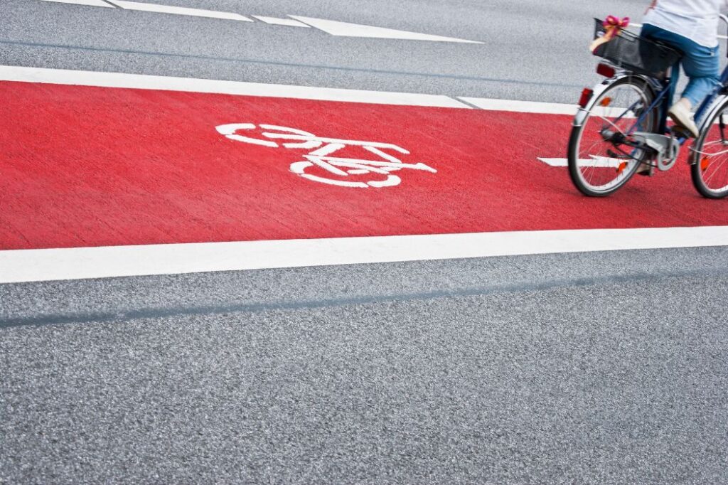 Fahrradfahrer auf rotem Radstreifen mit Piktogramm – Symbolbild für moderne Radwegplanung